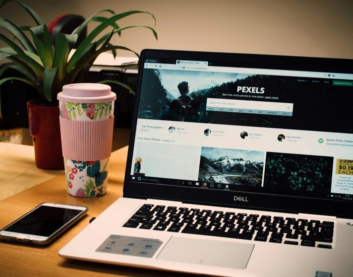 pexels-photo-811587-811587-1 A tidy desk setting with a laptop showing a stock photo website and a smartphone.